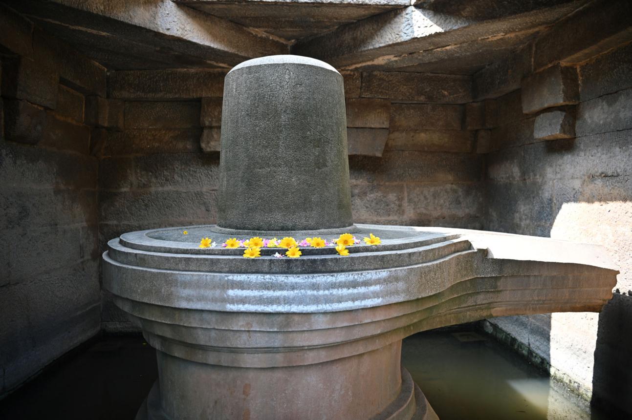 Stone Shiva Lingam in a temple setting with flowers